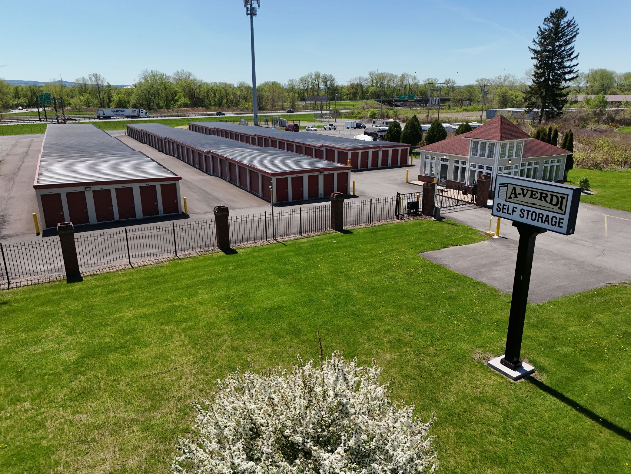 A-Verdi Self Storage facility entrance with roadside sign, gated access, office building, and red storage units.